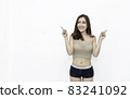 Attractive smiling positive asian happy woman finger point up over white background. Closeup portrait of beautiful asian girl wearing sport wear. People lifestyle concept 83241092