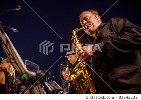 Male musician playing saxophone under blue night sky 83242132
