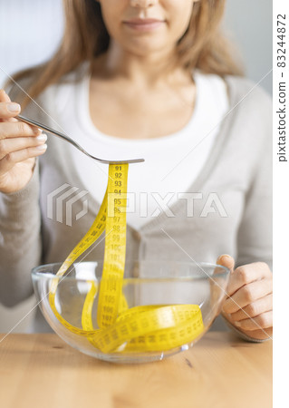 Young woman holding fork with measuring tapes. Young woman holding fork with measuring tapes. 83244872