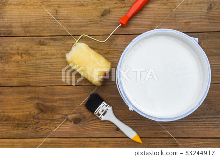 Painted tool with paint brush paint roller bucket canned paint for painting on wooden background, top view Painted tool with paint brush paint roller bucket canned paint for painting on wooden background, top view 83244917