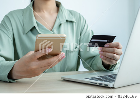 The businesswoman's hand is holding a credit card and using a smartphone for online shopping and internet payment in the office The businesswoman's hand is holding a credit card and using a smartphone for online shopping and internet payment in the office 83246169