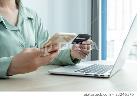 The businesswoman's hand is holding a credit card and using a smartphone for online shopping and internet payment in the office The businesswoman's hand is holding a credit card and using a smartphone for online shopping and internet payment in the office 83246170