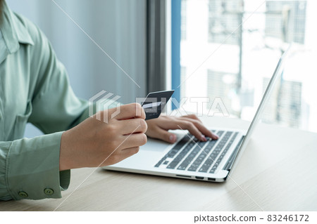 The businesswoman's hand is holding a credit card and using a laptop for online shopping and internet payment in the office The businesswoman's hand is holding a credit card and using a laptop for online shopping and internet payment in the office 83246172