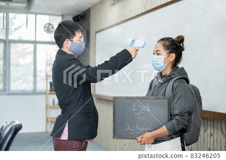 Back to school. Asian male teacher using thermometer temperature screening student for fever against the spread of COVID-19 Before entering the classroom. Virus protection concept Back to school. Asian male teacher using thermometer temperature screening student for fever against the spread of COVID-19 Before entering the classroom. Virus protection concept 83246205