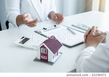 A real estate agent with a House model is talking to clients about buying home insurance. Home insurance concept 83246472