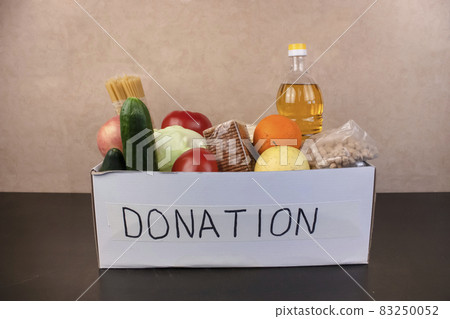 Donation box. Sunflower oil, peas, cookies, canned food, vegetables, apple, orange. Place for text, copy space 83250052
