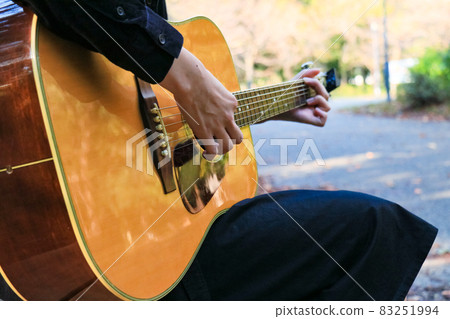 Scenery of playing an acoustic guitar in a forest park 83251994