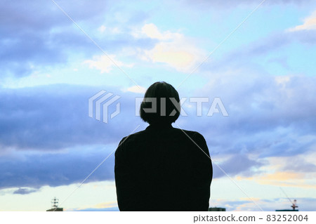 一個女人看著傍晚的天空和雲彩的背影 83252004