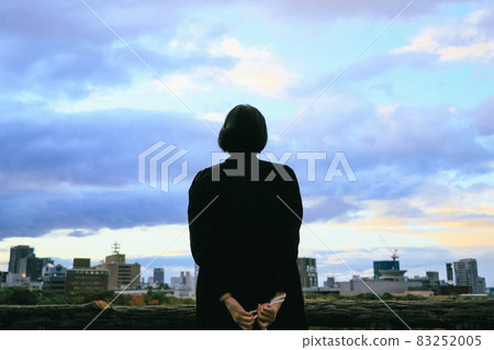 一個女人在日落時仰望天空和城市的背影 一個女人在日落時仰望天空和城市的背影 83252005