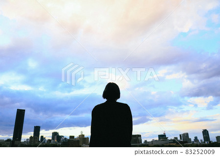 一個女人看著夕陽的天空的剪影 一個女人看著夕陽的天空的剪影 83252009