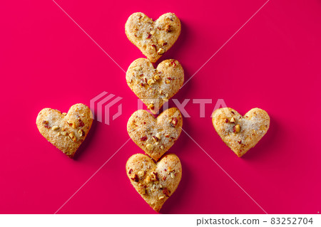 Heart shaped cookies for valentines day on pink background. Composition of almond cookies in the shape of a heart on a pink background 83252704
