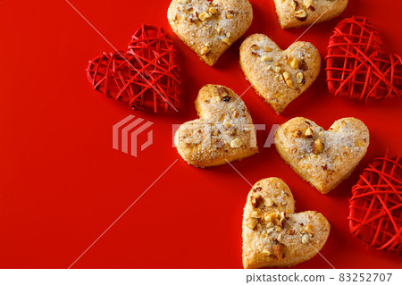 Heart shaped sugar cookies on red background. A lot of heart shaped cookies on a red background. Place for text, design for valentines day. Heart shaped sugar cookies on red background. A lot of heart shaped cookies on a red background. Place for text, design for valentines day. 83252707