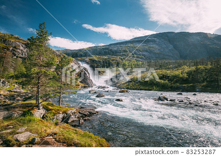 Kinsarvik, Hordaland, Norway. Waterfall Nykkjesoyfossen In Hardangervidda Mountain Plateau. Summer Sunny Day. Height Of 49 m. Famous Norwegian Landmark And Popular Destination Kinsarvik, Hordaland, Norway. Waterfall Nykkjesoyfossen In Hardangervidda Mountain Plateau. Summer Sunny Day. Height Of 49 m. Famous Norwegian Landmark And Popular Destination 83253287