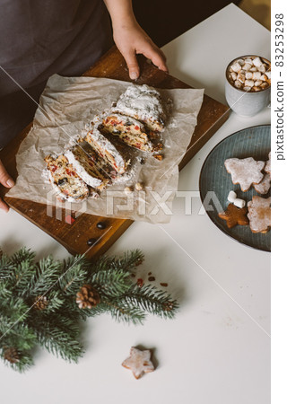 Woman serves Christmas pastries, stollen on a wooden board. Woman serves Christmas pastries, stollen on a wooden board. 83253298