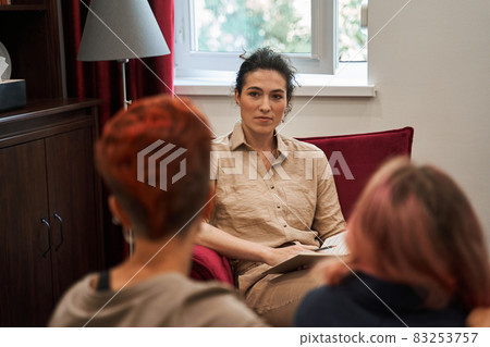 Woman supporting her girlfriend in therapy while listening curiously to the counselor Woman supporting her girlfriend in therapy while listening curiously to the counselor 83253757