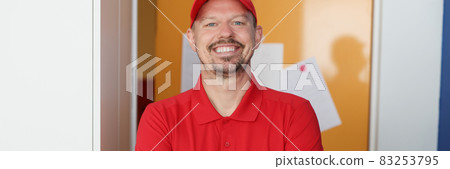 Portrait of smiling male courier in red uniform Portrait of smiling male courier in red uniform 83253795
