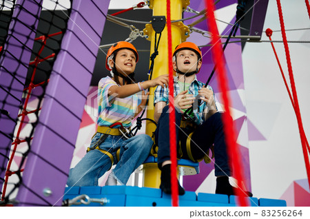 Two children in helmets climb on tightropes Two children in helmets climb on tightropes 83256264
