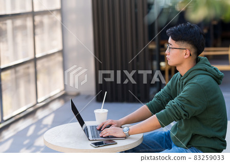 在咖啡館裡用電腦工作的年輕人 83259033