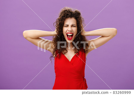 Ex-boyfriend spoilt woman formal event being outraged and pissed yelling in fury holding hands on curly hair grimacing from anger standing over purple background in stylish evening red dress Ex-boyfriend spoilt woman formal event being outraged and pissed yelling in fury holding hands on curly hair grimacing from anger standing over purple background in stylish evening red dress 83260999