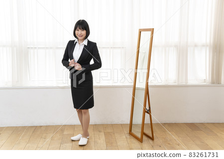 A woman wearing a suit in front of a full-length look 83261731