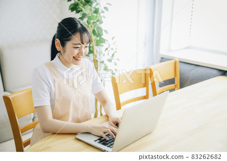 A woman in an apron using a computer (smile) 83262682