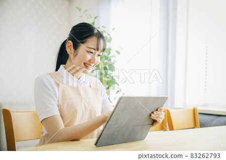A woman in an apron using a tablet PC 83262793