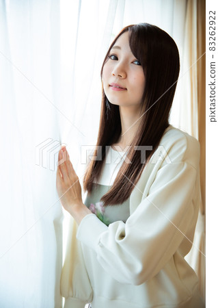 擺在窗簾前面的年輕日本婦女 擺在窗簾前面的年輕日本婦女 83262922