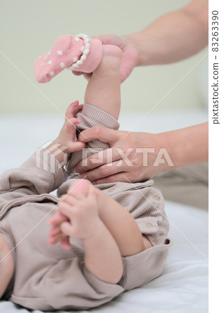 Mom putting socks on a baby in the second half of life 83263390