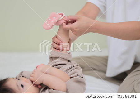 Mom putting socks on a baby in the second half of life Mom putting socks on a baby in the second half of life 83263391
