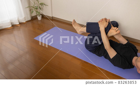 A man doing yoga and stretching at home. Gluteus maximus stretch. 83263853
