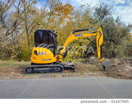 JCB digger or excavator performs excavation work outdoors 83267085