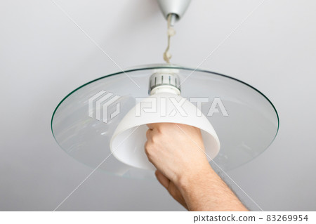 man installs lampshade of ceiling lamp 83269954