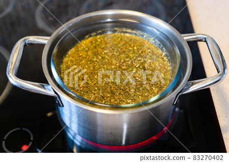 preparing tincture from herbs in water bath 83270402