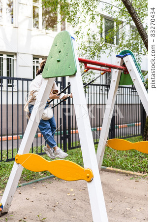 girl swinging on chain swing in city courtyard girl swinging on chain swing in city courtyard 83270434
