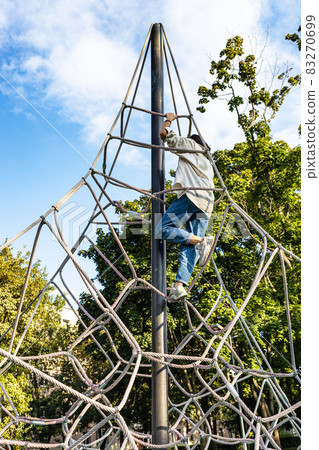girl climbs on rope playground in city courtyard 83270699