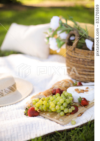 Picnic basket with food on green sunny lawn. 83270869