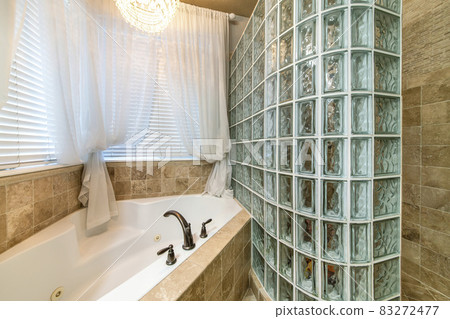 Bathroom interior with corner bathtub and stall with glass block wall Bathroom interior with corner bathtub and stall with glass block wall 83272477