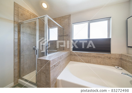 Shower stall and bathtub inside a bathroom with window Shower stall and bathtub inside a bathroom with window 83272498