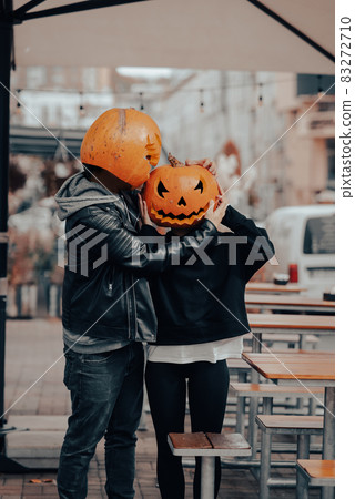 Guy and girl with pumpkin heads look at each other Guy and girl with pumpkin heads look at each other 83272710