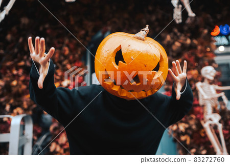 Girl with a pumpkin head scares at the camera Girl with a pumpkin head scares at the camera 83272760