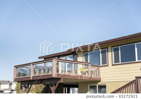 Terrace of a house with wooden handrails and glass panel 83272921