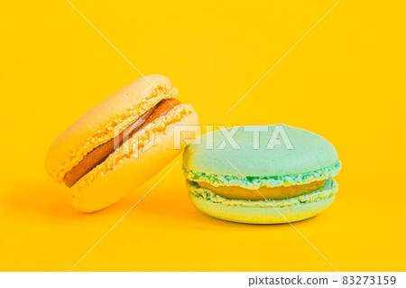 Sweet almond colorful unicorn blue yellow macaron or macaroon dessert cake isolated on trendy yellow modern fashion background. French sweet cookie. Minimal food bakery concept Copy space Sweet almond colorful unicorn blue yellow macaron or macaroon dessert cake isolated on trendy yellow modern fashion background. French sweet cookie. Minimal food bakery concept Copy space 83273159