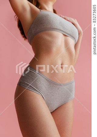 Close-up image of fit female body in gray underwear isolated over pink background. Close-up image of fit female body in gray underwear isolated over pink background. 83273605
