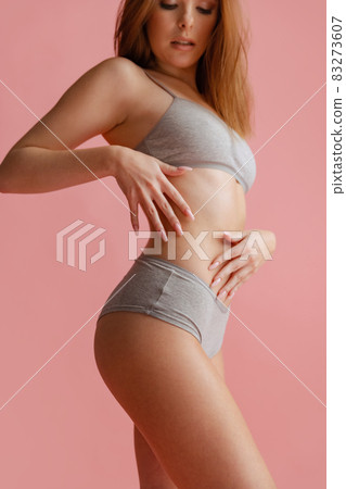 Cropped side view portrait of beautiful young woman in gray underwear posing isolated over pink background. Cropped side view portrait of beautiful young woman in gray underwear posing isolated over pink background. 83273607