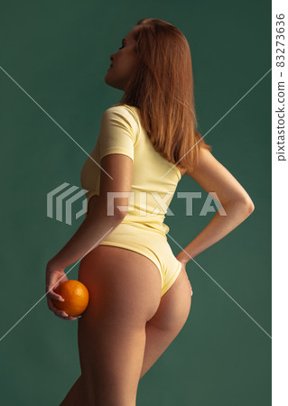 Cropped image of female body, back view in beige inner wear isolated over green background. Anti cellulite care Cropped image of female body, back view in beige inner wear isolated over green background. Anti cellulite care 83273636