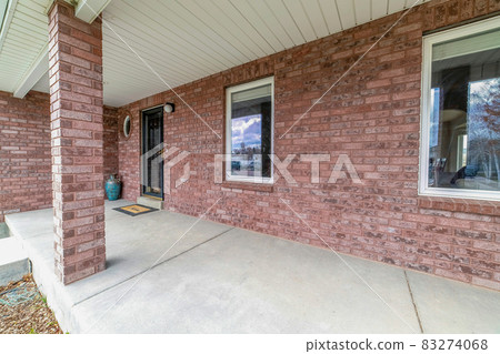 Spacious and open wrap around concrete porch of house with brick exterior wall Spacious and open wrap around concrete porch of house with brick exterior wall 83274068