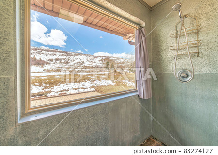 Shower room with large window with snowy grassy landscape and blue sky views Shower room with large window with snowy grassy landscape and blue sky views 83274127