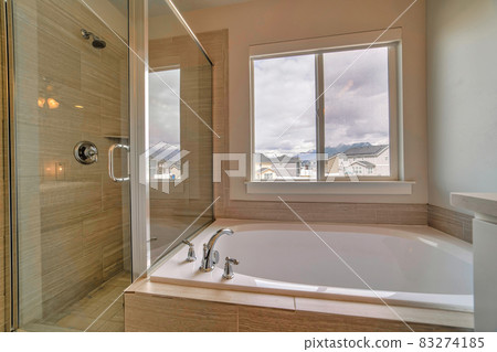 Shower stall with glass wall and door beside built in bathtub inside bathroom 83274185