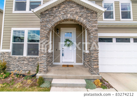 Beautiful facade of home with arched stone entrance and glass paned front door 83274212
