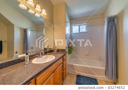 Sink on marble countertop over brown cabinets against mirror and bathroom lights 83274652